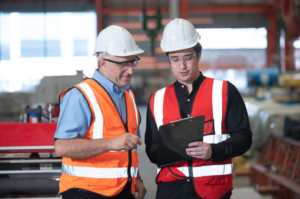 Industrial engineers in hard hats discuss new project in factory they work in a heavy industry manufacturing